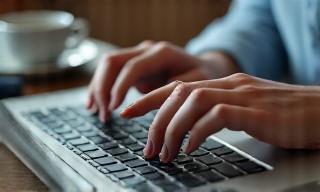Hands typing on a laptop, creating engaging blog content